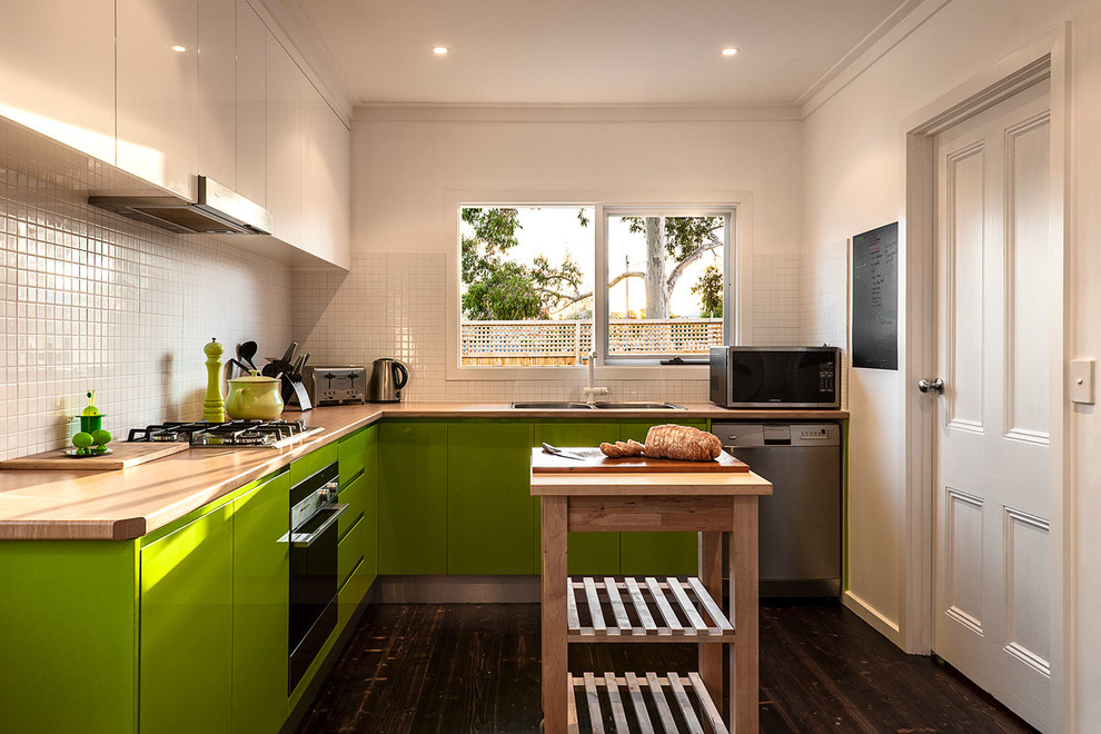 メルボルンにあるコンテンポラリースタイルのおしゃれなキッチン (ドロップインシンク、フラットパネル扉のキャビネット、緑のキャビネット、木材カウンター、白いキッチンパネル、セラミックタイルのキッチンパネル、白い調理設備、濃色無垢フローリング) の写真