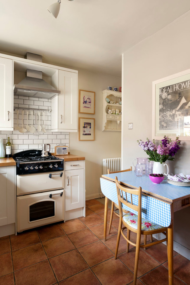 Klassische Wohnküche mit Schrankfronten mit vertiefter Füllung, weißen Schränken, Arbeitsplatte aus Holz, Küchenrückwand in Weiß, Rückwand aus Metrofliesen und weißen Elektrogeräten in Surrey
