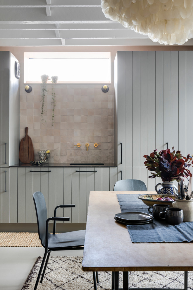 На фото: кухня в стиле лофт с обеденным столом, серыми фасадами, столешницей из известняка, бетонным полом, серым полом, черной столешницей, одинарной мойкой и розовым фартуком