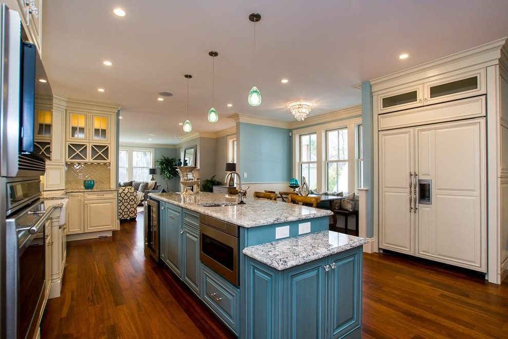 Design ideas for a large victorian u-shaped open plan kitchen in Boston with a belfast sink, raised-panel cabinets, white cabinets, white splashback, stainless steel appliances, medium hardwood flooring, an island and brown floors.