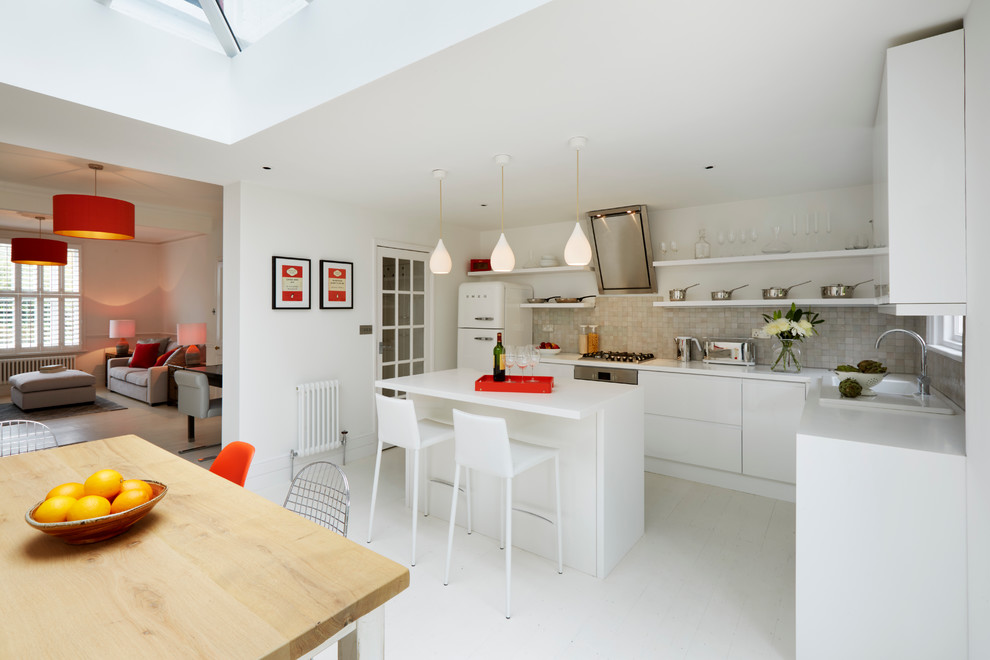 Moderne Wohnküche in L-Form mit Einbauwaschbecken, offenen Schränken, weißen Schränken, Mineralwerkstoff-Arbeitsplatte, weißen Elektrogeräten, gebeiztem Holzboden, Kücheninsel und Küchenrückwand in Grau in Kent