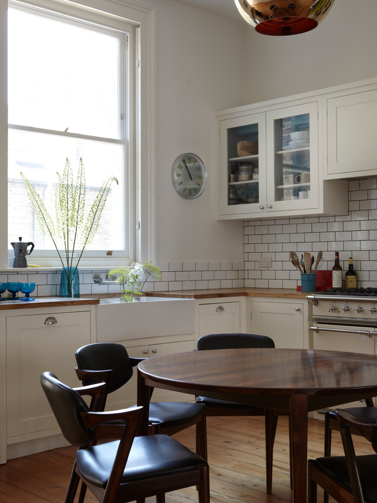 Inredning av ett modernt stort kök, med en undermonterad diskho, skåp i shakerstil, vita skåp, träbänkskiva, vitt stänkskydd, stänkskydd i keramik, rostfria vitvaror och ljust trägolv