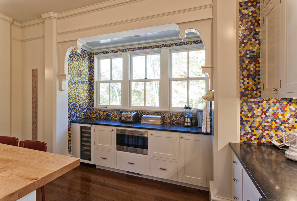 Bild på ett mellanstort vintage kök, med en undermonterad diskho, släta luckor, vita skåp, granitbänkskiva, flerfärgad stänkskydd, stänkskydd i keramik, mellanmörkt trägolv, en köksö och rostfria vitvaror