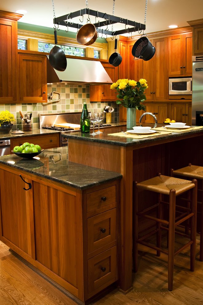 Eat-in kitchen - large traditional l-shaped medium tone wood floor and brown floor eat-in kitchen idea in Detroit with shaker cabinets, dark wood cabinets, granite countertops, multicolored backsplash, ceramic backsplash, stainless steel appliances and an island