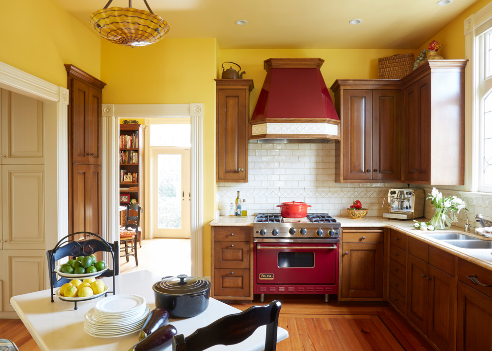 Bild på ett avskilt, mellanstort vintage l-kök, med en dubbel diskho, luckor med upphöjd panel, skåp i mörkt trä, marmorbänkskiva, vitt stänkskydd, stänkskydd i keramik, färgglada vitvaror, mellanmörkt trägolv och brunt golv
