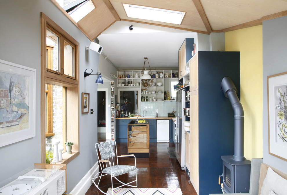 Exempel på ett eklektiskt l-kök, med en nedsänkt diskho, skåp i shakerstil, blå skåp, träbänkskiva, vitt stänkskydd, stänkskydd i keramik, rostfria vitvaror, mörkt trägolv och en köksö