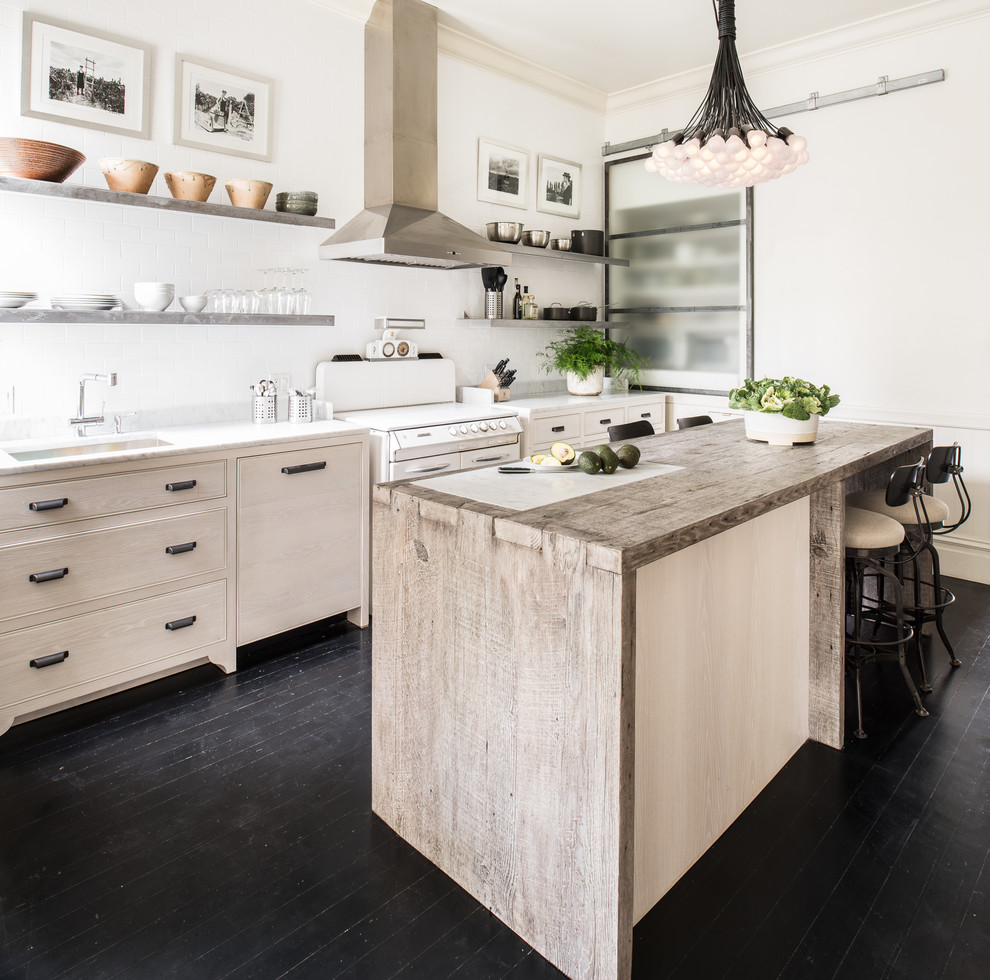 Inspiration for a mid-sized eclectic single-wall dark wood floor enclosed kitchen remodel in San Francisco with an undermount sink, flat-panel cabinets, light wood cabinets, marble countertops, white backsplash, ceramic backsplash, stainless steel appliances and an island