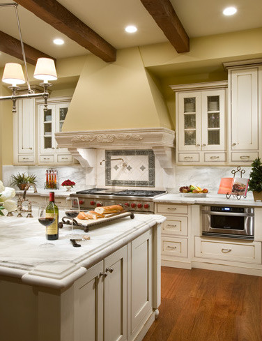 Klassische Küche mit flächenbündigen Schrankfronten, weißen Schränken, braunem Holzboden und Kücheninsel in Orange County