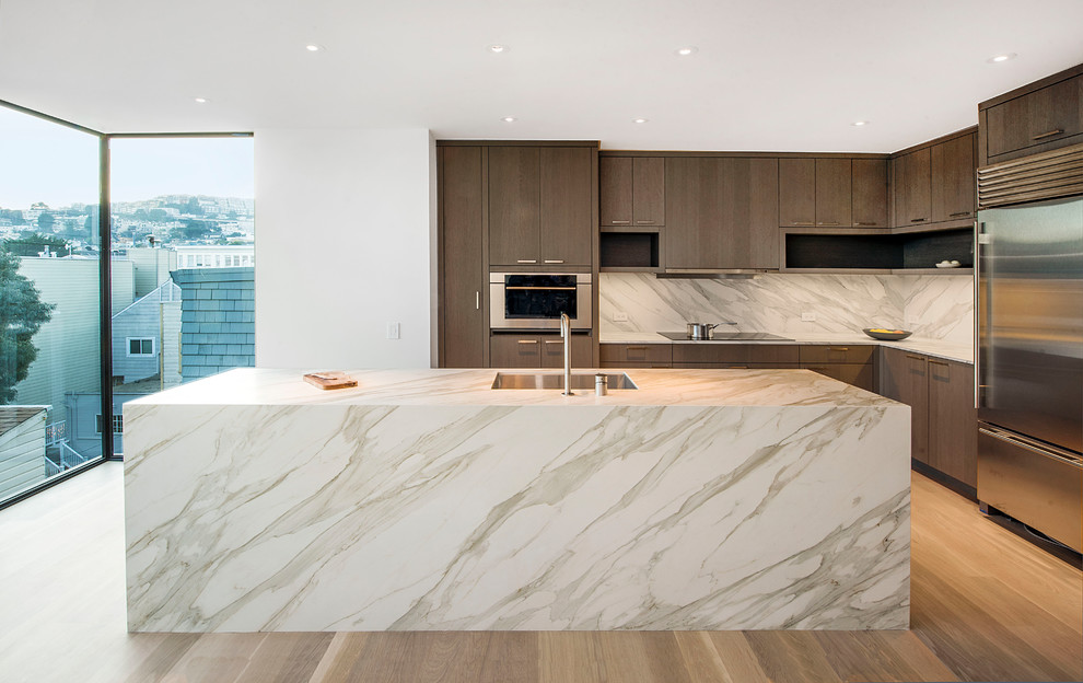 Photo of a medium sized contemporary l-shaped kitchen/diner in San Francisco with a submerged sink, flat-panel cabinets, dark wood cabinets, stainless steel appliances, an island, white worktops, marble worktops, grey splashback, porcelain splashback, dark hardwood flooring and brown floors.