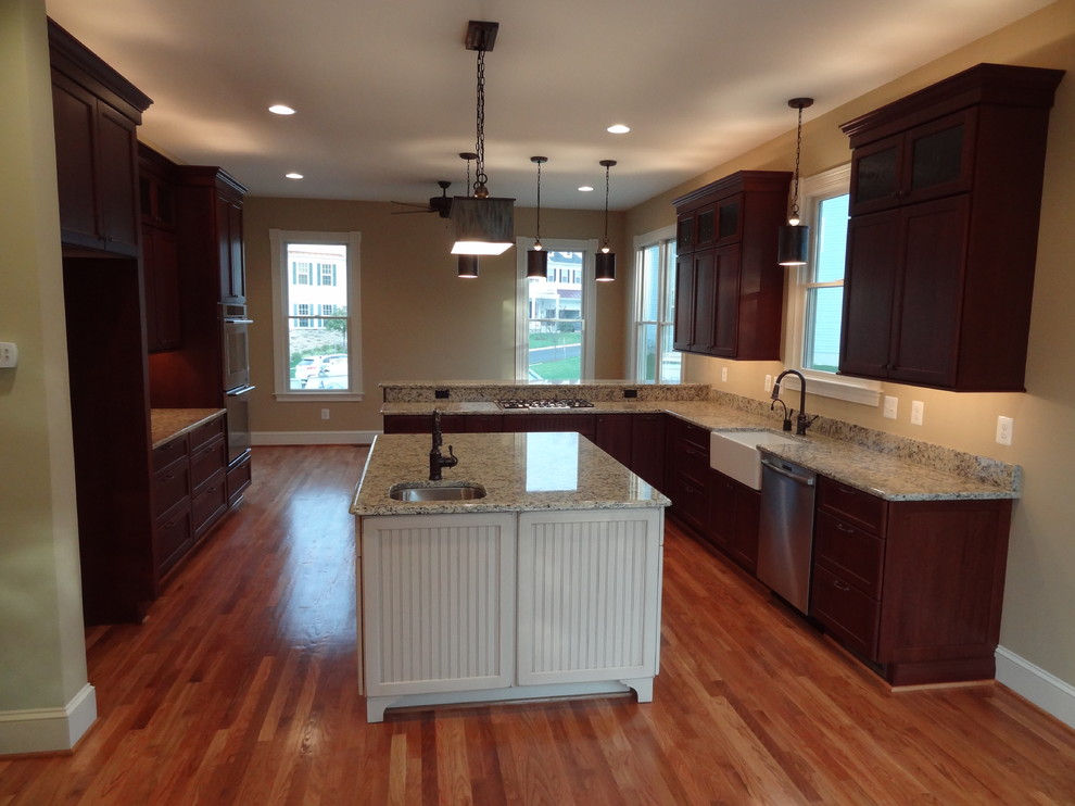 Inspiration for a medium sized rural u-shaped kitchen/diner in Baltimore with a belfast sink, shaker cabinets, dark wood cabinets, granite worktops, stainless steel appliances, medium hardwood flooring and an island.