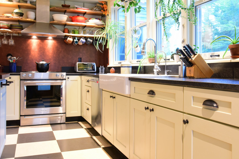 Photo of a victorian l-shaped kitchen/diner in Boston with a belfast sink, recessed-panel cabinets, white cabinets, black splashback, stainless steel appliances and an island.