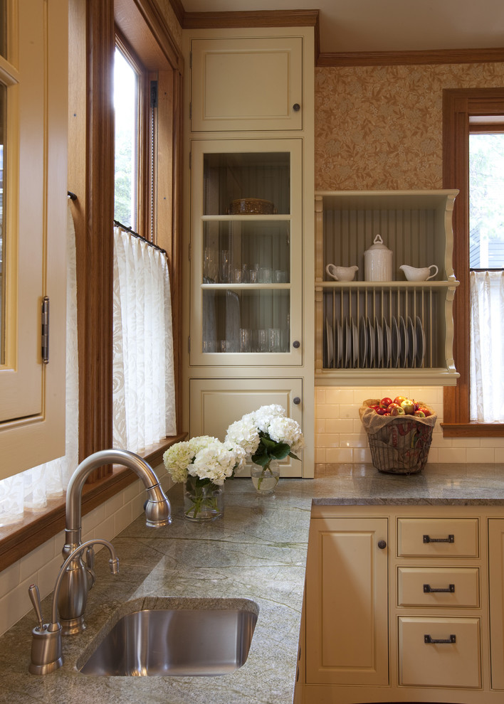 Modelo de cocina tradicional con armarios con rebordes decorativos, salpicadero de azulejos tipo metro, fregadero de un seno, encimera de granito y puertas de armario beige