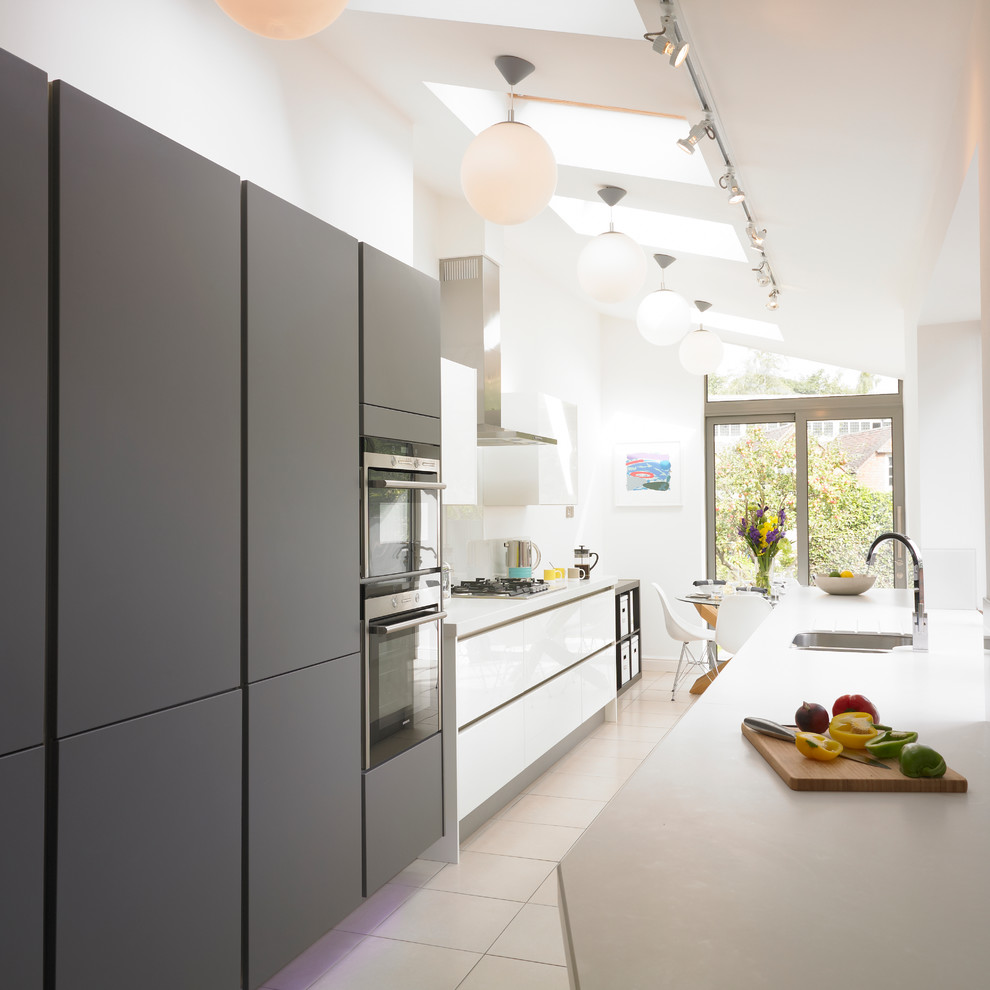 Diseño de cocina comedor gris y blanca contemporánea pequeña con fregadero bajoencimera, armarios con paneles lisos, puertas de armario grises y electrodomésticos de acero inoxidable