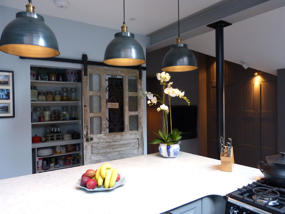 This is an example of a medium sized industrial u-shaped kitchen in Oxfordshire with a double-bowl sink, raised-panel cabinets, grey cabinets, composite countertops, medium hardwood flooring and no island.
