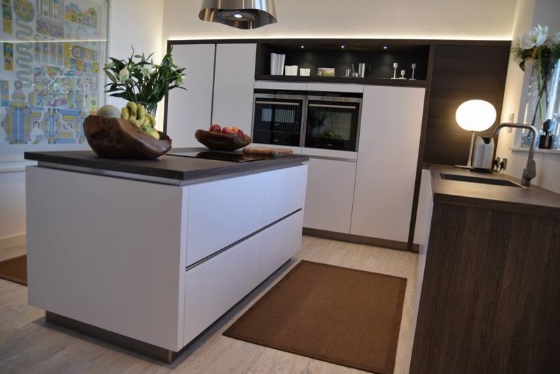 Medium sized modern l-shaped kitchen/diner in Other with a single-bowl sink, flat-panel cabinets, white cabinets, laminate countertops, brown splashback, coloured appliances, light hardwood flooring and an island.
