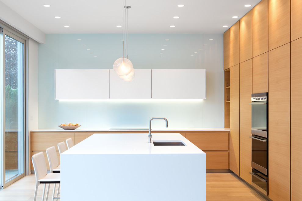 Design ideas for a modern kitchen in Vancouver with flat-panel cabinets, glass sheet splashback and an island.