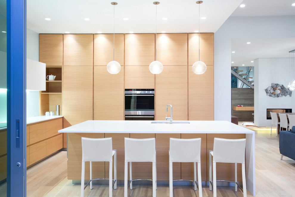 Minimalist light wood floor kitchen photo in Vancouver with an undermount sink, flat-panel cabinets, light wood cabinets, quartzite countertops, paneled appliances and an island