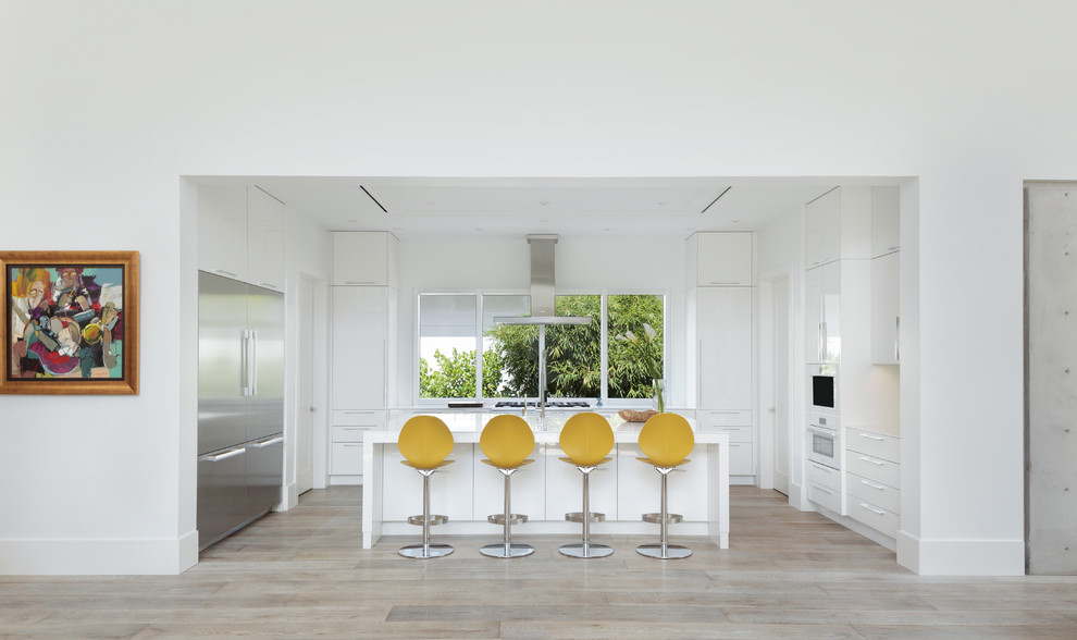 Example of a large trendy u-shaped medium tone wood floor open concept kitchen design in Miami with an undermount sink, flat-panel cabinets, yellow cabinets, quartzite countertops, white backsplash, stainless steel appliances and an island