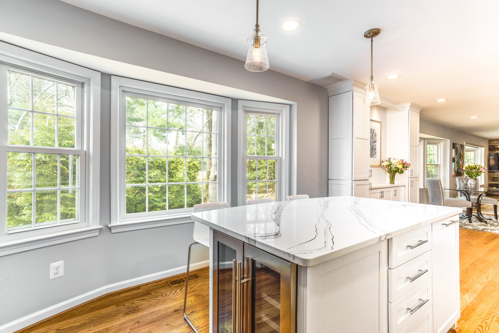 Photo of a small traditional l-shaped kitchen/diner in DC Metro with a submerged sink, recessed-panel cabinets, white cabinets, engineered stone countertops, multi-coloured splashback, ceramic splashback, stainless steel appliances, light hardwood flooring, an island and white worktops.