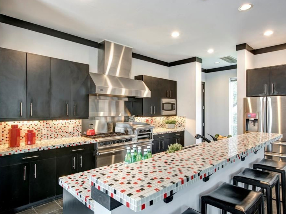 Idéer för mellanstora funkis flerfärgat kök, med en undermonterad diskho, släta luckor, svarta skåp, bänkskiva i glas, flerfärgad stänkskydd, stänkskydd i mosaik, rostfria vitvaror, klinkergolv i porslin, en köksö och svart golv