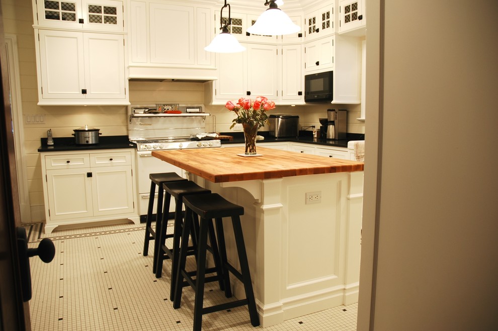 Photo of a large traditional u-shaped enclosed kitchen in Chicago with a belfast sink, recessed-panel cabinets, white cabinets, granite worktops, white appliances, porcelain flooring and an island.