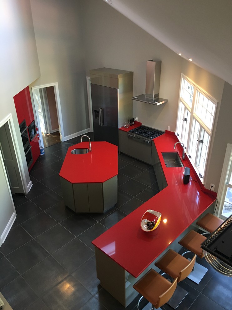 Пример оригинального дизайна: большая п-образная кухня-гостиная в стиле модернизм с врезной мойкой, плоскими фасадами, красными фасадами, столешницей из кварцевого агломерата, красным фартуком, техникой из нержавеющей стали, островом и серым полом