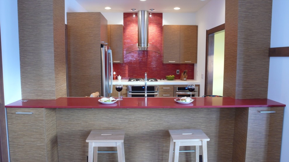 Modelo de cocina minimalista con armarios con paneles lisos, puertas de armario de madera clara y electrodomésticos de acero inoxidable