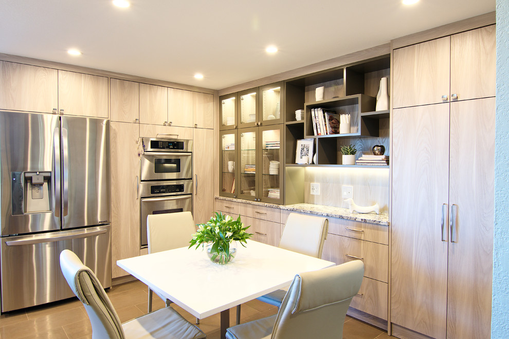 Exemple d'une grande cuisine moderne en U et bois clair avec un placard à porte plane, un plan de travail en granite, une crédence grise, une crédence en mosaïque et un électroménager en acier inoxydable.