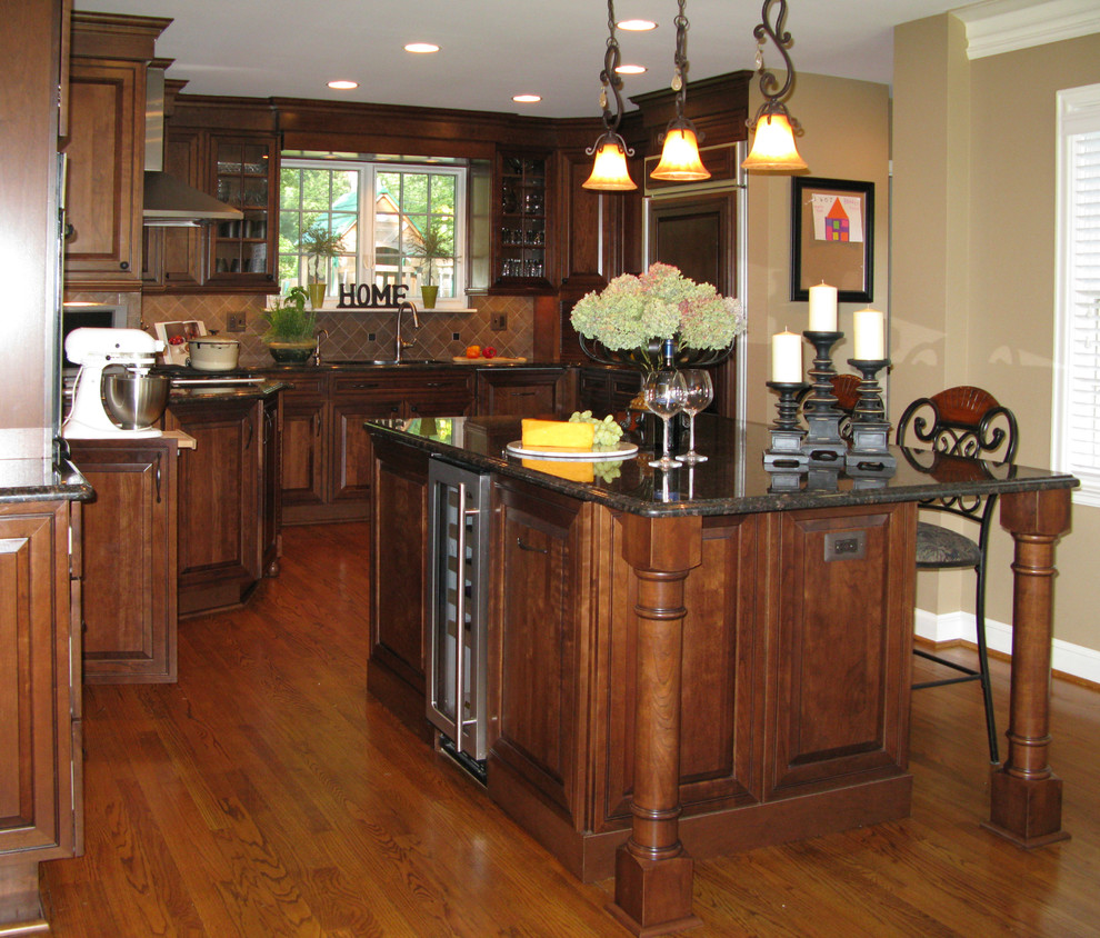 Eat-in kitchen - large traditional u-shaped medium tone wood floor and brown floor eat-in kitchen idea in Detroit with an undermount sink, raised-panel cabinets, medium tone wood cabinets, granite countertops, brown backsplash, ceramic backsplash, an island and paneled appliances