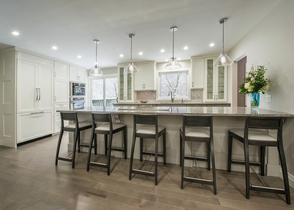 Open concept kitchen - mid-sized transitional l-shaped medium tone wood floor open concept kitchen idea in Toronto with an undermount sink, shaker cabinets, gray cabinets, quartzite countertops, gray backsplash, a peninsula, mosaic tile backsplash and paneled appliances