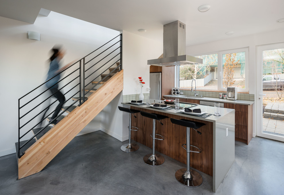 Contemporary galley kitchen in Seattle with an integrated sink, flat-panel cabinets, medium wood cabinets, granite worktops, grey splashback, stainless steel appliances, concrete flooring and a breakfast bar.