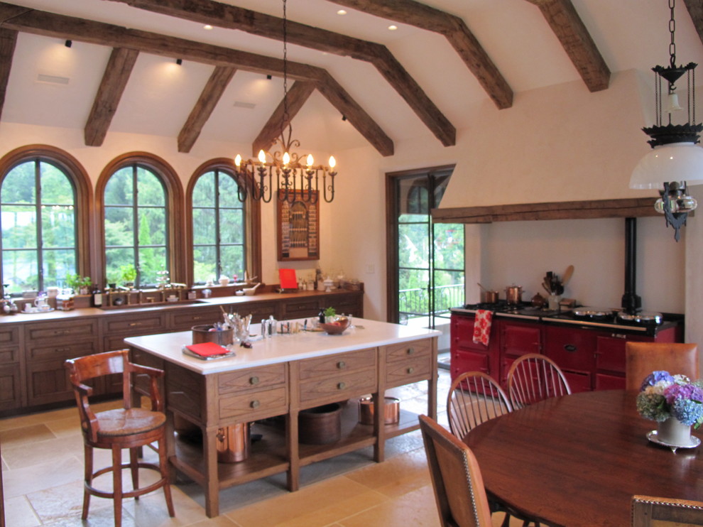 Foto på ett stort medelhavsstil linjärt kök med öppen planlösning, med en nedsänkt diskho, träbänkskiva, integrerade vitvaror, kalkstensgolv, en köksö och luckor med infälld panel