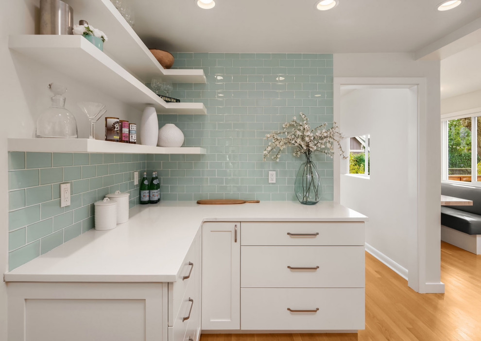 Kitchen - transitional light wood floor kitchen idea in Seattle with an undermount sink, shaker cabinets, white cabinets, quartz countertops, green backsplash, glass tile backsplash, stainless steel appliances and white countertops