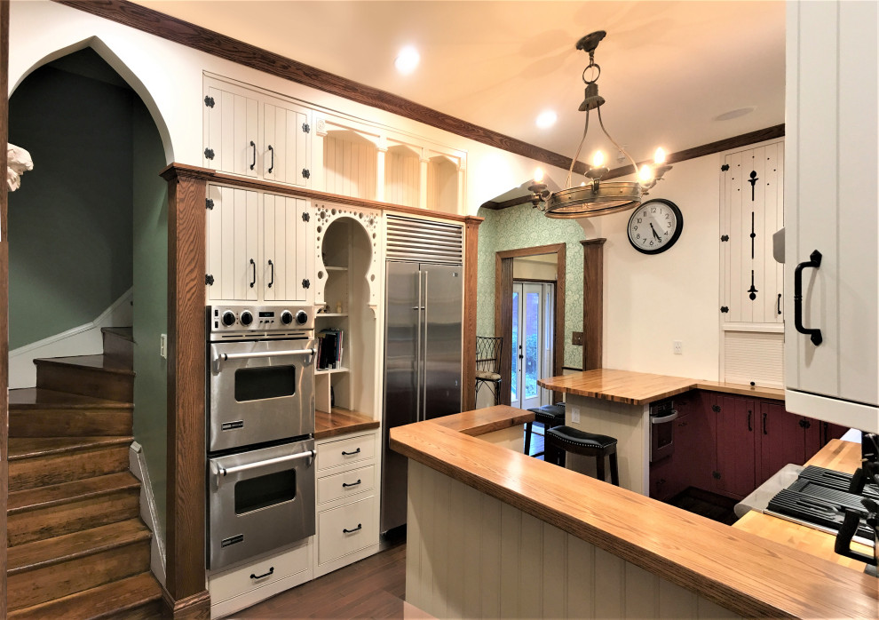 Foto på ett stort vintage brun kök, med en rustik diskho, luckor med profilerade fronter, vita skåp, träbänkskiva, grönt stänkskydd, stänkskydd i porslinskakel, rostfria vitvaror, mellanmörkt trägolv, brunt golv och en köksö