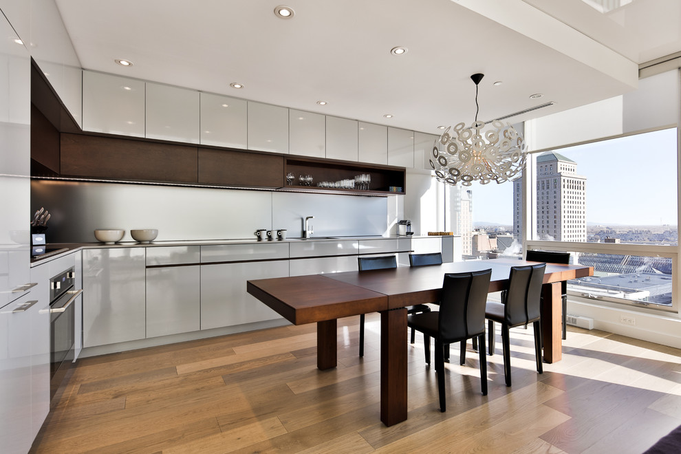 Moderne Küche in L-Form mit flächenbündigen Schrankfronten, grauen Schränken und braunem Holzboden in Montreal