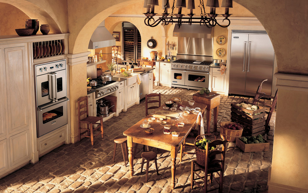 Foto di una grande cucina rustica con lavello stile country, ante a filo, ante bianche, top in granito, elettrodomestici in acciaio inossidabile, pavimento in mattoni e nessuna isola