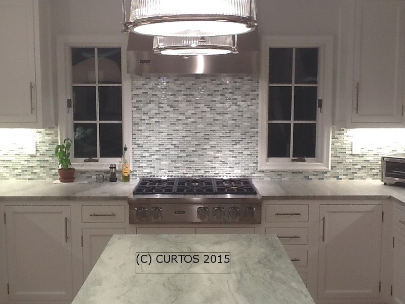 Klassische Wohnküche mit Schrankfronten mit vertiefter Füllung, weißen Schränken, Küchenrückwand in Grau, Küchengeräten aus Edelstahl und Kücheninsel in New York