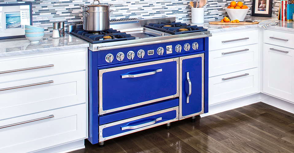 Immagine di una cucina stile shabby con elettrodomestici colorati e pavimento in legno massello medio