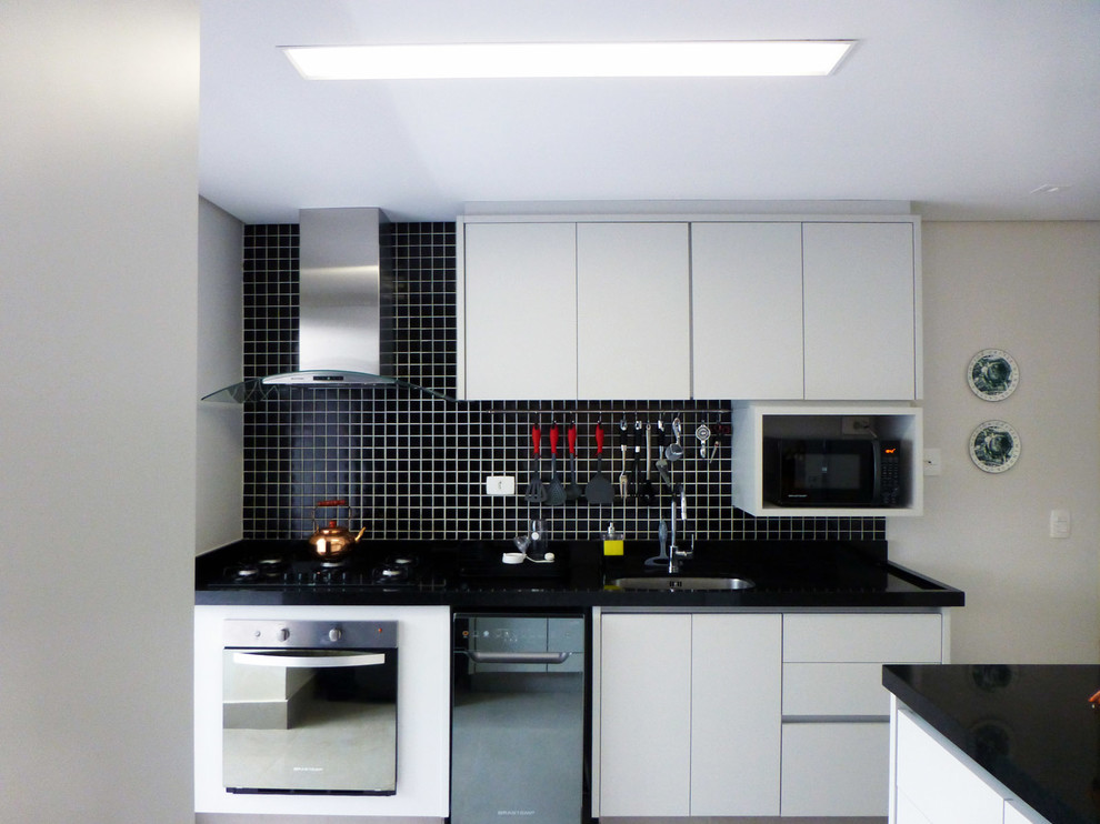 Inspiration för mellanstora moderna l-kök, med en enkel diskho, släta luckor, grå skåp, granitbänkskiva, svart stänkskydd, stänkskydd i mosaik, rostfria vitvaror och klinkergolv i porslin