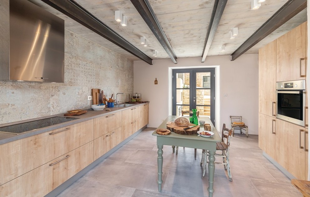 Foto di una cucina mediterranea con lavello integrato, ante lisce, ante in legno chiaro, paraspruzzi beige, elettrodomestici in acciaio inossidabile, pavimento grigio e top grigio