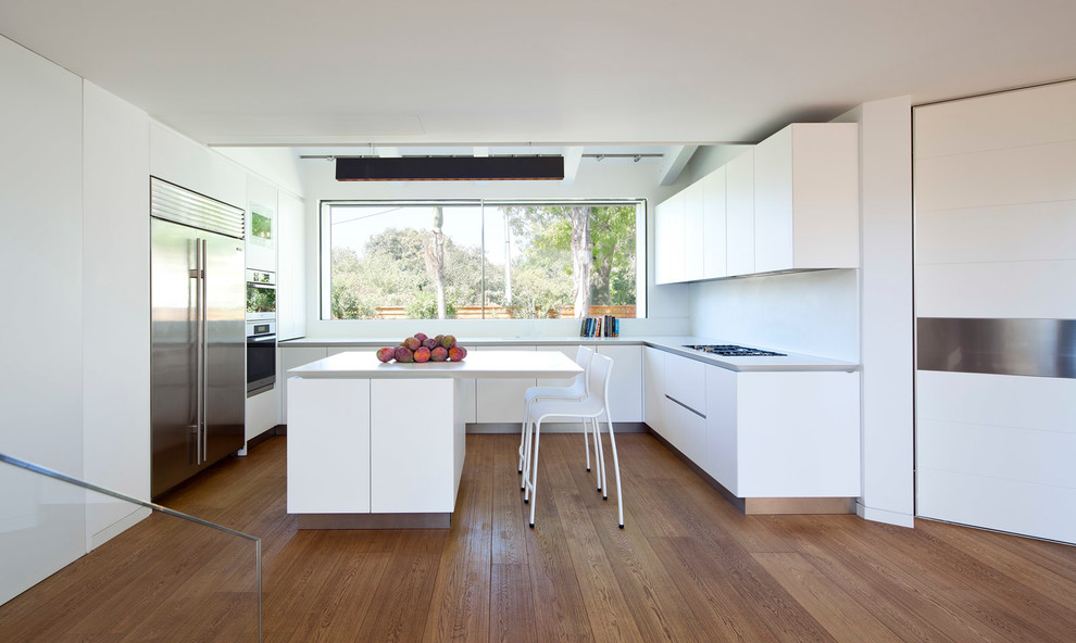 Moderne Küche in U-Form mit flächenbündigen Schrankfronten, weißen Schränken, Küchenrückwand in Weiß und Küchengeräten aus Edelstahl in Tel Aviv