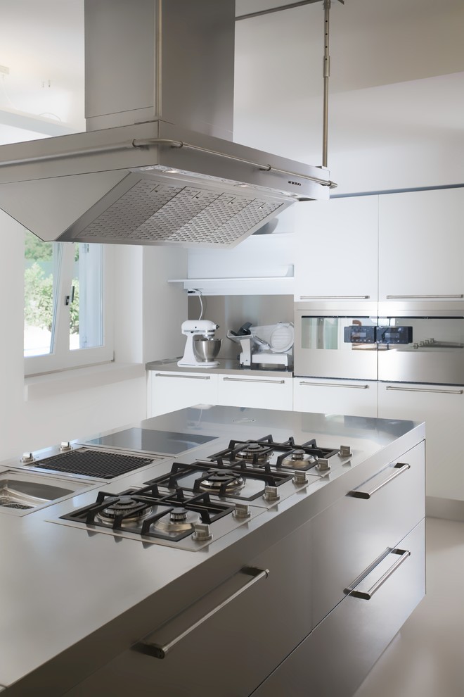 Idéer för ett modernt linjärt kök, med släta luckor, vita skåp, bänkskiva i rostfritt stål, rostfria vitvaror, klinkergolv i porslin och en köksö