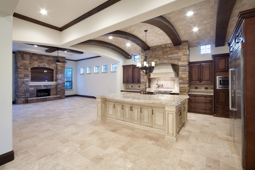 Inspiration for a large mediterranean travertine floor open concept kitchen remodel in Orlando with a farmhouse sink, raised-panel cabinets, dark wood cabinets, granite countertops, beige backsplash, stone tile backsplash, stainless steel appliances and an island