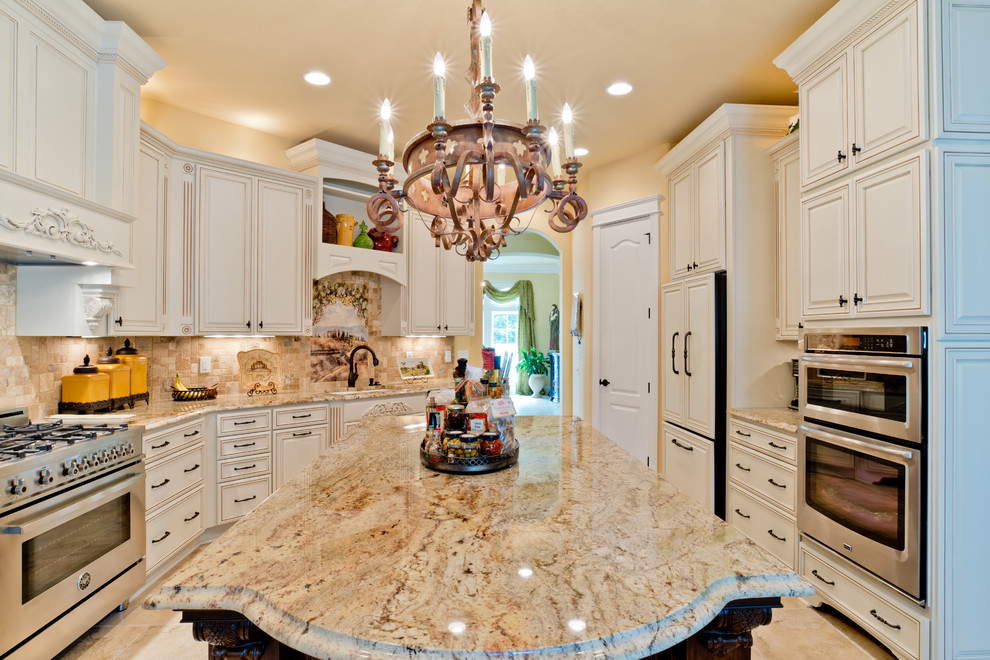 Eat-in kitchen - large mediterranean u-shaped porcelain tile eat-in kitchen idea in Miami with an undermount sink, raised-panel cabinets, white cabinets, granite countertops, beige backsplash, porcelain backsplash, stainless steel appliances and an island