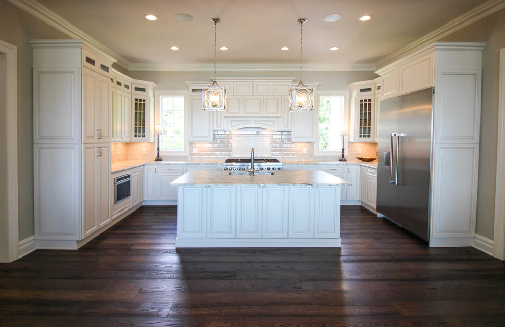 This is an example of a large traditional u-shaped kitchen in New York with a submerged sink, raised-panel cabinets, white cabinets, stainless steel appliances and an island.