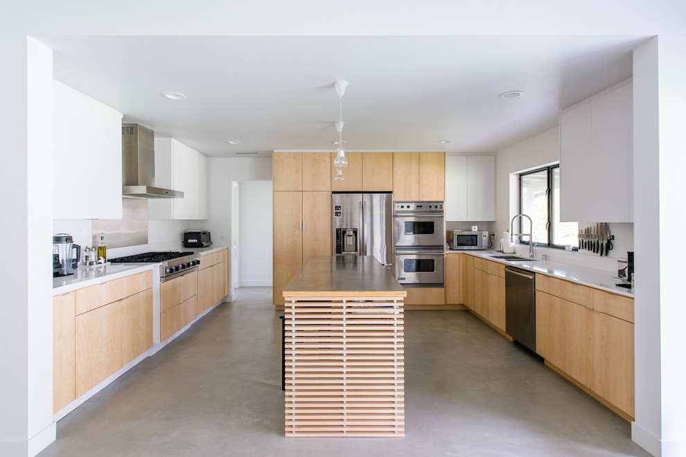 Exempel på ett stort modernt kök, med en undermonterad diskho, släta luckor, skåp i ljust trä, bänkskiva i kvarts, vitt stänkskydd, rostfria vitvaror, betonggolv och en köksö