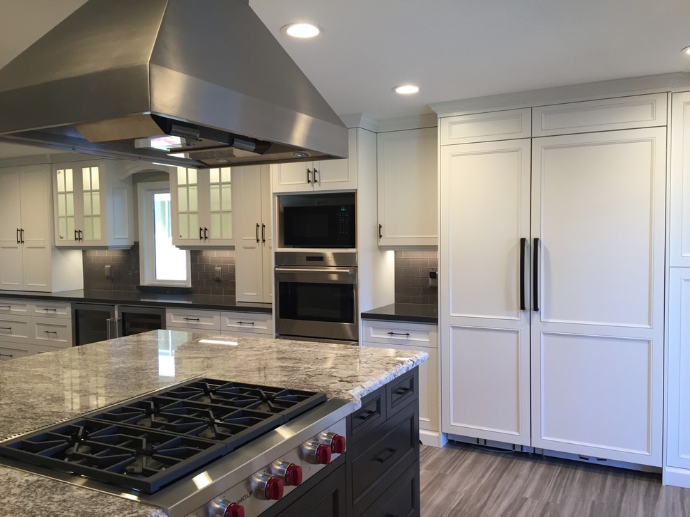 Foto di un cucina con isola centrale classico con ante in stile shaker, ante bianche, top in granito, pavimento marrone e top multicolore