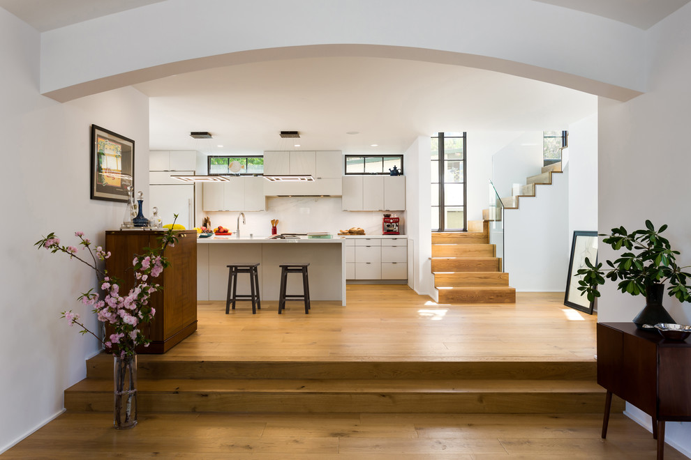 Bild på ett mellanstort medelhavsstil kök, med en undermonterad diskho, släta luckor, grå skåp, marmorbänkskiva, vitt stänkskydd, stänkskydd i marmor, rostfria vitvaror, ljust trägolv, en köksö och gult golv