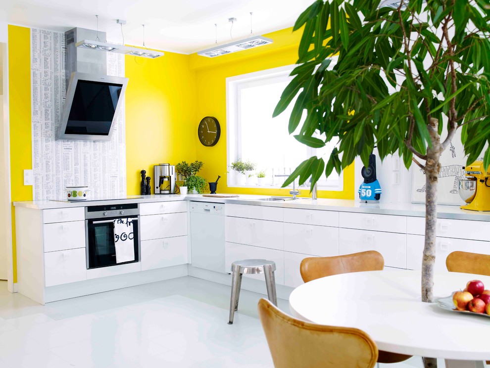 This is an example of a medium sized contemporary l-shaped kitchen/diner in Stockholm with a single-bowl sink, flat-panel cabinets, white cabinets, concrete worktops, stainless steel appliances and no island.