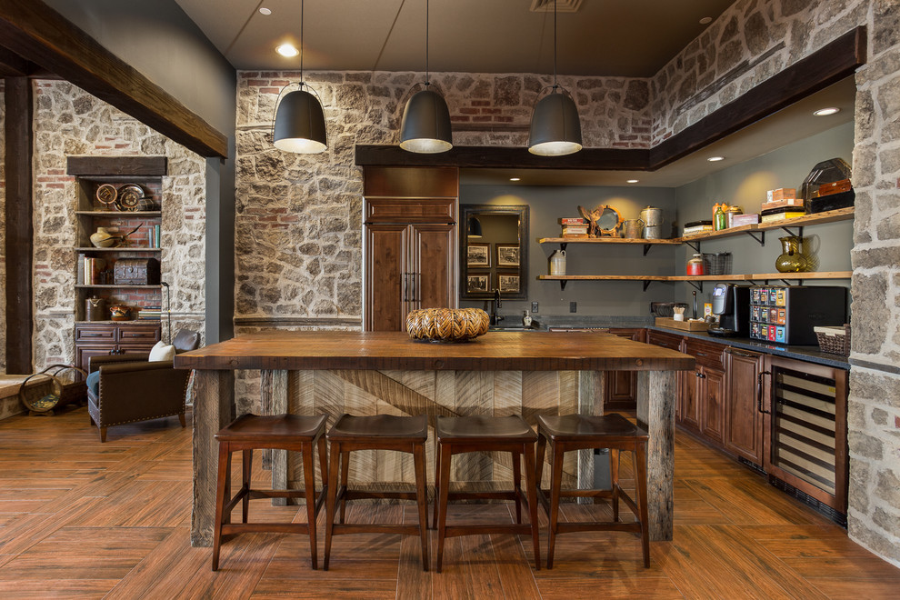 Diseño de cocinas en L de estilo americano con armarios abiertos, salpicadero verde, electrodomésticos con paneles, suelo de madera en tonos medios, una isla y pared de piedra